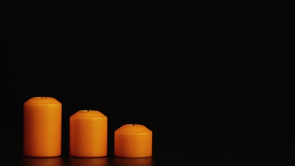 Três velas amarelas acesas em um fundo preto se apagam. Espaço de cópia. — Vídeo de Stock