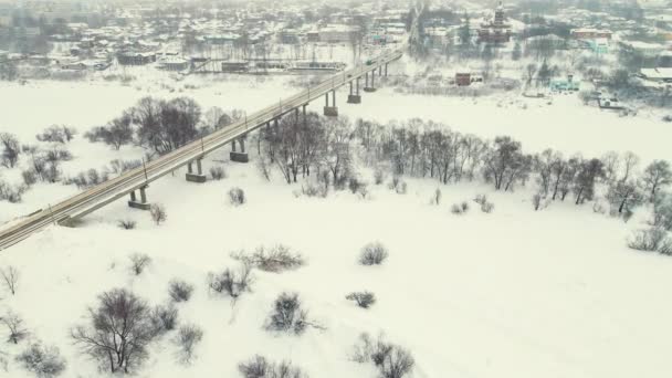 Báječná zimní krajina se zamrzlou řekou a silničním mostem, letecký pohled. — Stock video