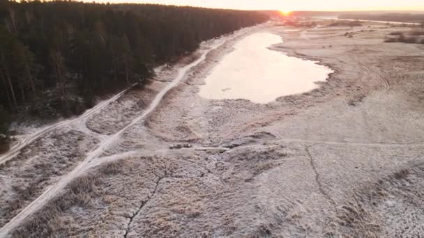 Pole, las i jezioro pod śniegiem w pomarańczowym świetle słońca. — Wideo stockowe