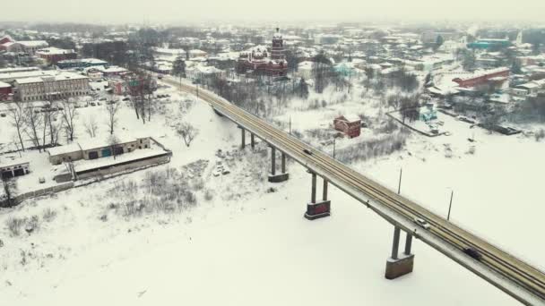 Klidná zimní krajina se zamrzlou řekou a silničním mostem, letecký pohled. — Stock video