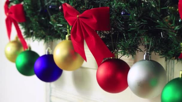 Mooie Kerst kleurrijke ballen hangen op een bloemenslinger van een groene tak. — Stockvideo