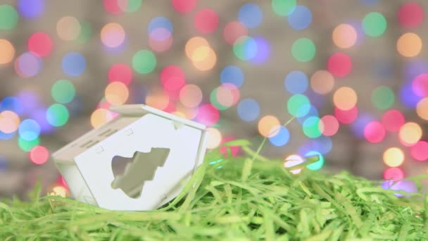 Vánoční spořič bílé hračky dům na pozadí novoroční světla. — Stock video