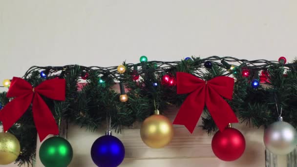 Πολύχρωμα χριστουγεννιάτικα μπαλάκια κρέμονται από μια γιρλάντα ενός πράσινου κλαδιού.. — Αρχείο Βίντεο