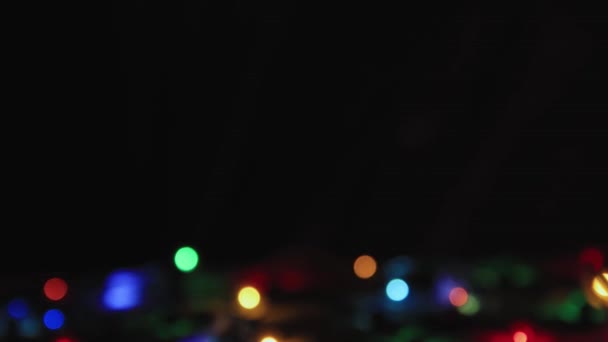 Luces de Navidad de colores sobre un fondo negro abajo, espacio para copiar. — Vídeos de Stock