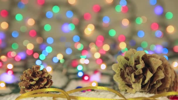 Salvapantallas de Año Nuevo dos conos de pino en el fondo de las luces de Navidad — Vídeos de Stock