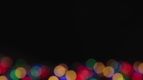 Iluminado misteriosamente luzes de Natal coloridas em um fundo preto, espaço de cópia. — Vídeo de Stock