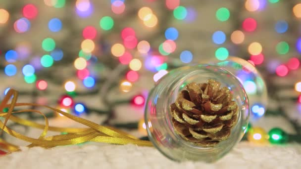 Nový rok stříkací sklo s borovým kuželem na pozadí vánoční světla. — Stock video