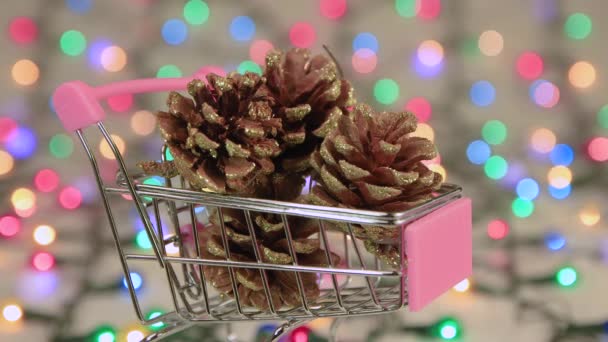 Screensaver pine cones in a cart against a background of Christmas lights. — Stock Video