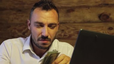 Sıkıntılı bir işadamı kameraya bakar, bir tomar dolar tutar ve kaybeder.