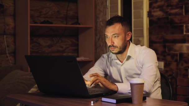 Knappe zakenman in een wit shirt werkt aandachtig, typt op het toetsenbord. — Stockvideo