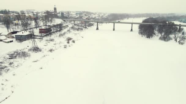 Величественный зимний пейзаж с замерзшей рекой и автомобильным мостом, вид с воздуха. — стоковое видео