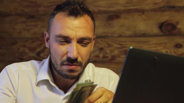 Een noodlijdende zakenman kijkt naar de camera, houdt een bundel dollars vast, verliezen. — Stockvideo