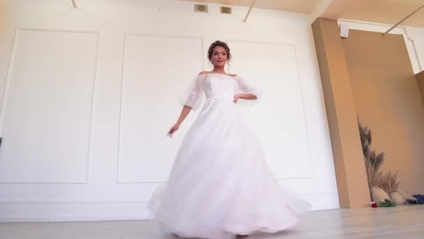 Uma noiva bonita em um vestido branco posa para um fotógrafo de pé, gira. — Vídeo de Stock