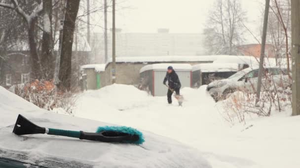 Un hombre despeja un camino con una pala cerca de su casa. — Vídeos de Stock