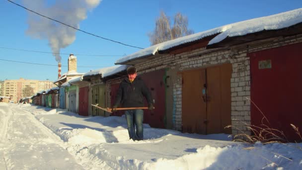 Un hombre saca nieve de un camino fuera de su garaje — Vídeos de Stock