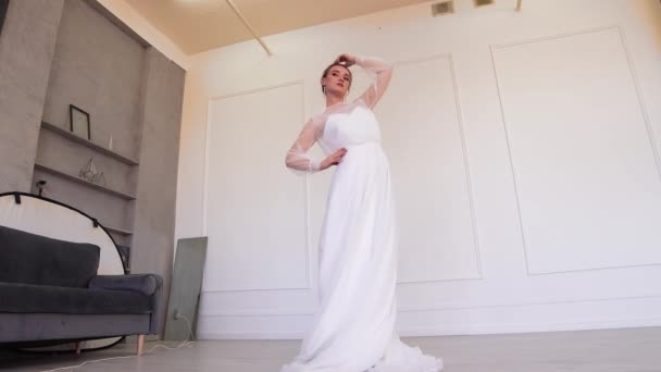Belle mariée dans une robe blanche posant pour le photographe tout en étant debout. — Video