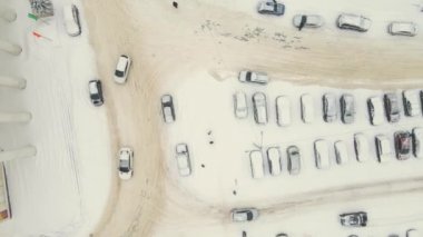 Şiddetli bir kar fırtınasından sonra arabalar karla kaplı bir otoparkta yavaşça ilerler..
