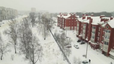 Üç katlı tuğla evler kışın karla kaplı bir şehir caddesinde.