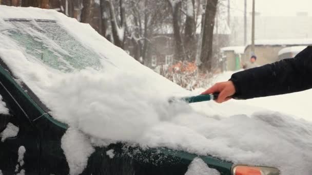 Bir adam kaputtaki karı ve arabanın ön camını fırçayla temizliyor.. — Stok video