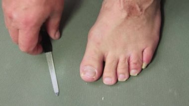 Adamın biri elinde metal bir dosya ile ayak tırnağını gıcırdatıyor.. 