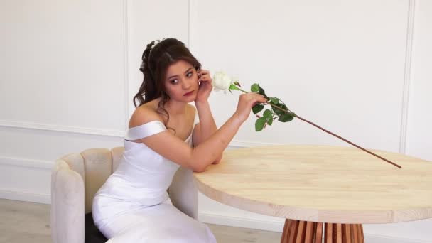 Sposa alla moda in un abito bianco in posa per il fotografo mentre seduto. — Video Stock