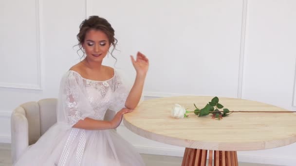 Pengantin cantik dengan gaun putih berpose untuk fotografer sambil duduk. — Stok Video