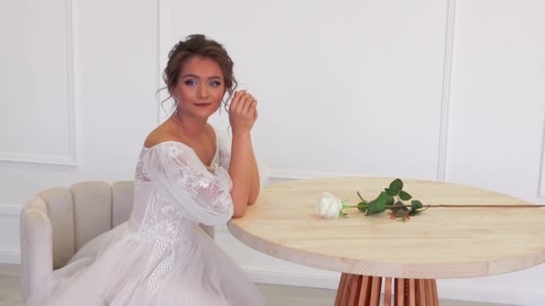 La sposa in un abito bianco posa per il fotografo mentre siede a tavola — Video Stock
