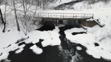 Fırtınalı bir nehir, köprü ve hava manzaralı kış manzarası.. 