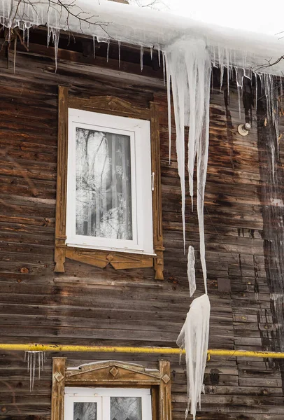 Bahar şeffaf buz sarkıtları çatıda ve bacada asılı.
