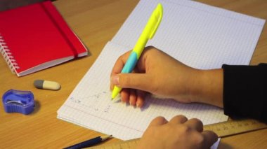 Lise öğrencisinin elleri dikkatle matematiği defterde çözüyor.. 