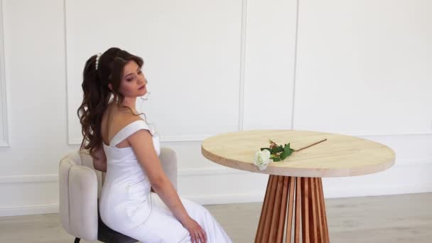 Élégante mariée en robe blanche posant pour le photographe assis. — Video