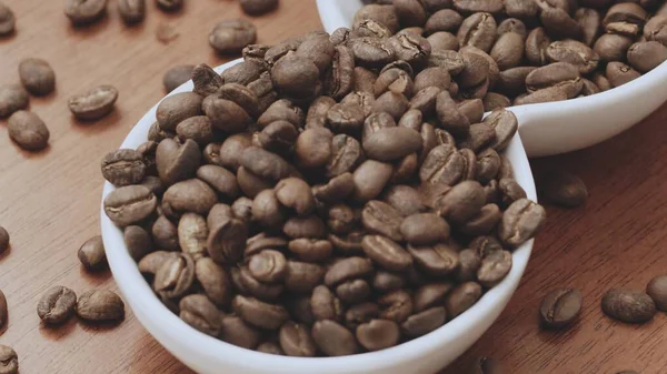 kavrulmuş kahve çekirdekleri beyaz kase ahşap masada.