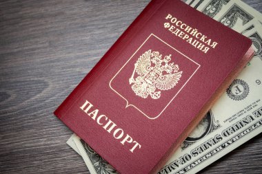Ahşap bir arka planda yabancı bir pasaport ve dolar. Belge ve banknotların fotoğrafları.