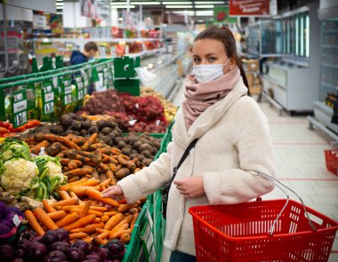 Maskeli bir kız, marketten alışveriş yapıyor. İzole edilmiş Covid-19 salgını.