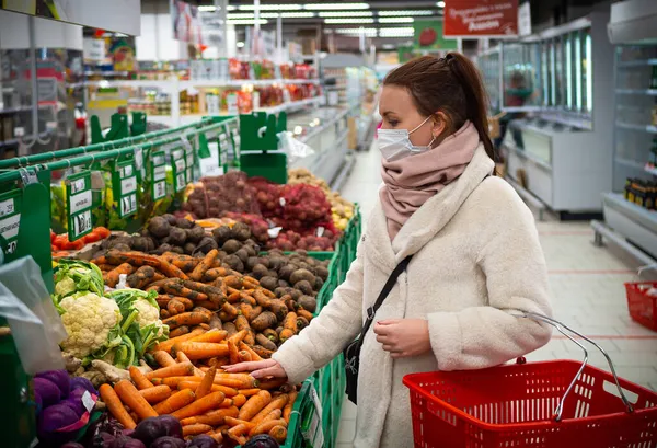 Maskeli bir kız, marketten alışveriş yapıyor. İzole edilmiş Covid-19 salgını.