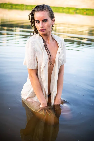 カメラの前の砂の上に立つ濡れたシャツの美しいブルネットのモデル 全長撮影 — ストック写真