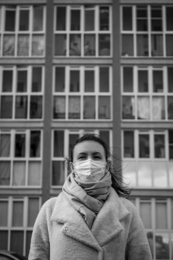 Korunmak için sokakta yüz maskesi takan bir kızı vurdular. Pencereli bir apartmanın arka planına karşı. Covid-19 salgınını engelle.