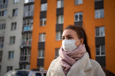 Korunmak için sokakta yüz maskesi takan bir kızı vurdular. Pencereli bir apartmanın arka planına karşı. Covid-19 salgınını engelle.