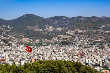 Türkiye 'nin sallanan bayrağı. Alanya şehrinin arka planına ve dağlara karşı.