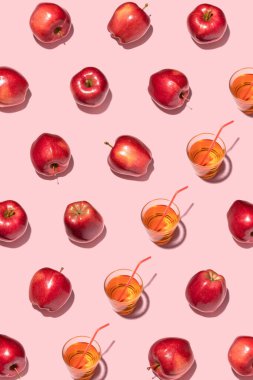 Pembe arka planda kırmızı elmalar ve meyve suyu. Şablon, üst manzara, düz yatış.