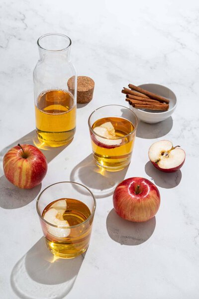 Fresh red apples and apple juice in glasses and bottle on a light background. Fruits and drinks. Top view, copy space.
