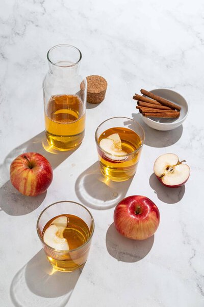 Fresh red apples and apple juice in glasses and bottle on a light background. Fruits and drinks. Top view, copy space.