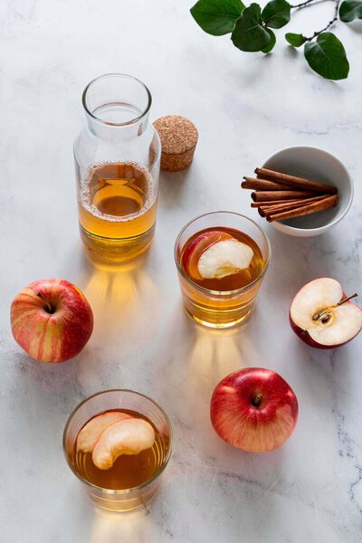 Fresh red apples and apple juice in glasses and bottle on a light background. Fruits and drinks. Top view, copy space.