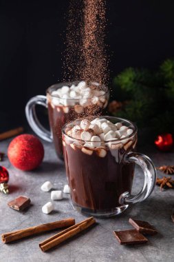 Camdan bardağa sıcak çikolata ve marşmelov damlatarak. Uzayı kopyala Karanlık arka plan. Alçakgönüllülük. Kış, Noel ve Yeni Yıl yiyecek ve içecek konsepti.