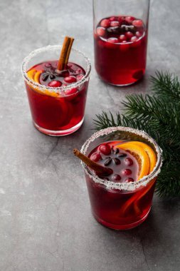 Kış için sıcak sıcak şarap, yabanmersini, baharat, tarçın ve cam bardakta portakal dilimleri ve gri masada bir şişe. Noel içkisi. Noel ağacı dallarıyla şenlikli bir konsept. Seçici odak.
