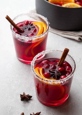 Noel için sıcak şarap, kızılcık, baharat, tarçın ve portakal dilimleri ile beyaz masada iki cam bardak içinde. Seçici odak.