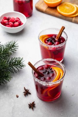 Kış için sıcak sıcak şarap, kızılcık, baharat, tarçın ve portakal dilimleri iki cam bardak ve beyaz masa üzerinde şişe. Noel ağacı dallarıyla şenlikli bir konsept. Seçici odak.