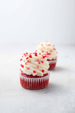 Krem peynir kremalı kırmızı kadife kek ve üstüne kırmızı kalpler serpiştirilmiş. Sevgililer Günü konsepti. Seçici odak.