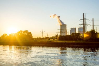 Gün batımında nehirde kömürle çalışan elektrik santrali