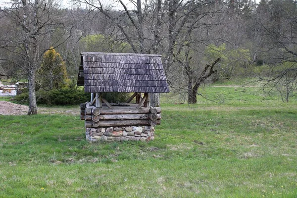 Sebuah sumur kayu tua dengan atap yang kuat di pinggiran desa — Stok Foto